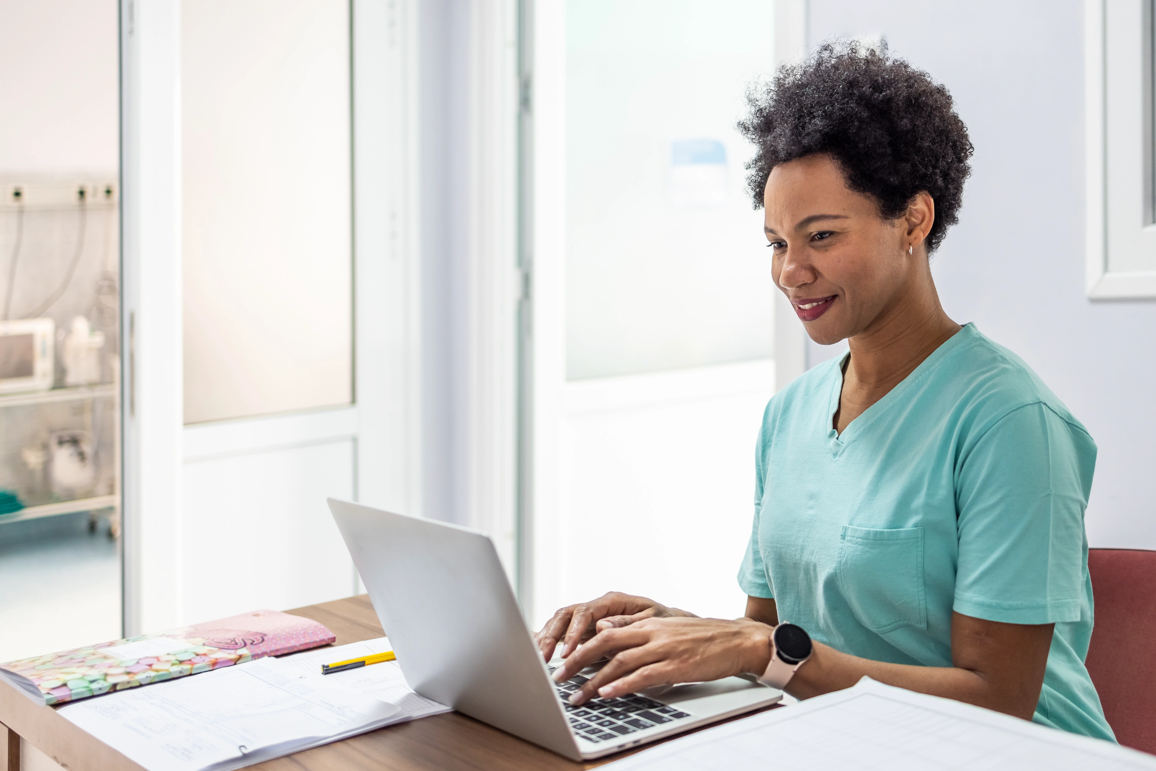 Nurse in scrubs taking a continuing education course on her laptop at a desk